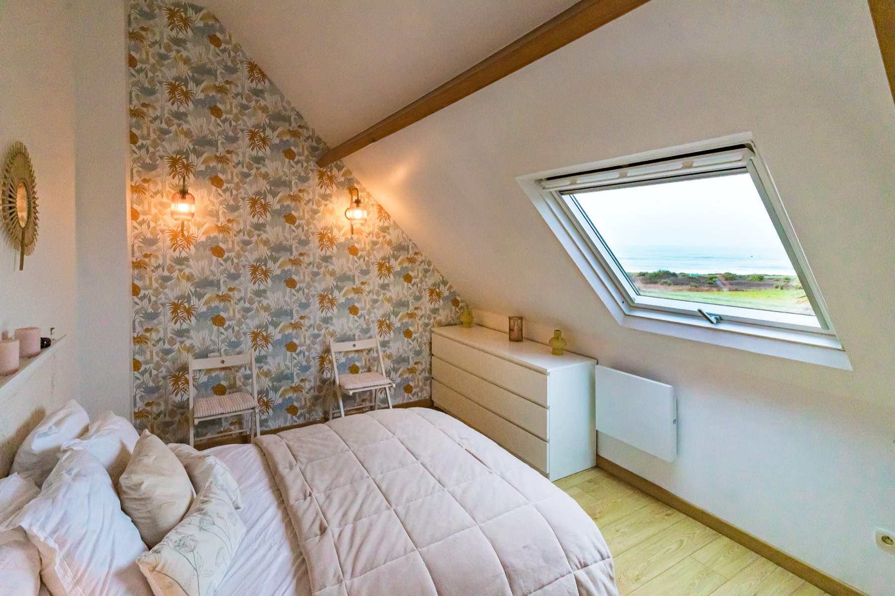 Chambre aux tons pastel avec grande fenêtre sur la mer